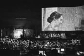 Große Videoproduktion in der Nono-Inszenierung. Davor Chor, Solisten und Orchester. 