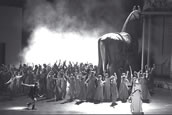 Martin Dvorrák (Tänzer) und Tanja Ariane Baumgartner (Cassandre) sowie im Hintergrund Chor und Extrachor der Oper Frankfurt mit Chorgästen. Foto: Barbara Aumüller